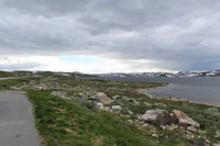 A paved road near a body of water under a cloudy sky